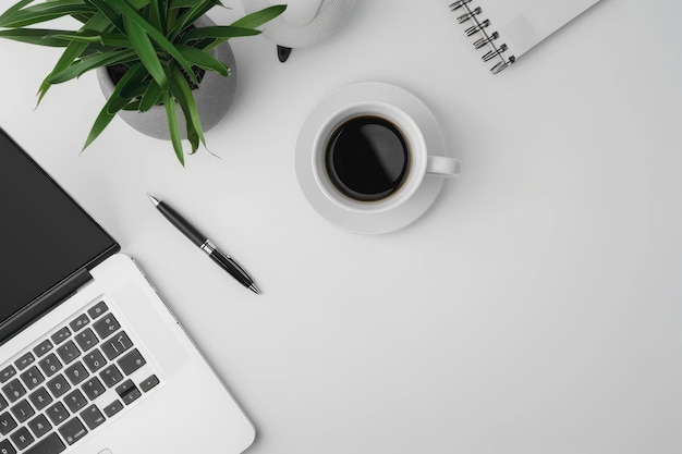 a minimalist white table with a laptop coffee cup notebook and pen leaving space at the top