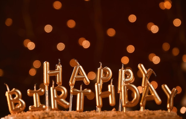 Minimalistic background with golden candles without fire letters in cake close up