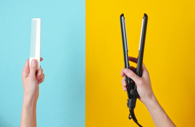 Minimalistic beauty and fashion still life. Woman's hands holding comb and hair straightener on blue yellow.