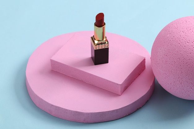 Minimalistic beauty scene or showcase with lipstick and pink platforms on blue background