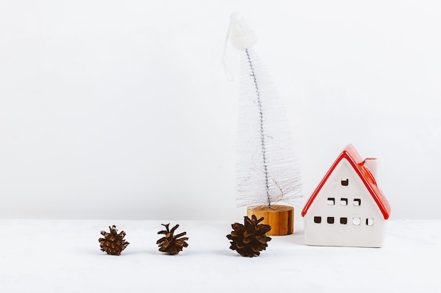 Minimalistic Christmas background Ceramic house with red roof cones and Christmas tree Concept zero west