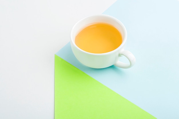 Minimalistic geometric composition with cup of asian green tea on blue and green