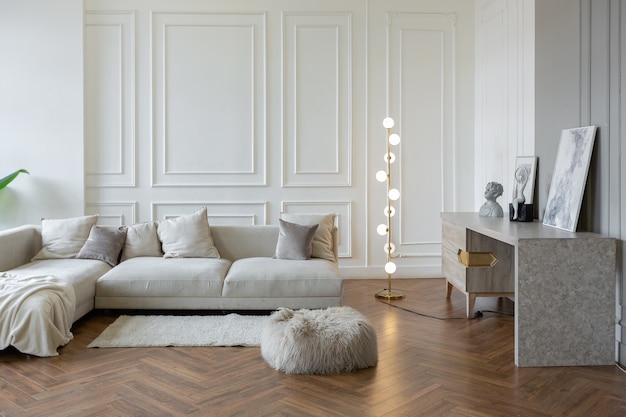 Minimalistic interior of an ultra modern open plan apartment with white and gray walls with a relief and gray stylish upholstered furniture and huge windows