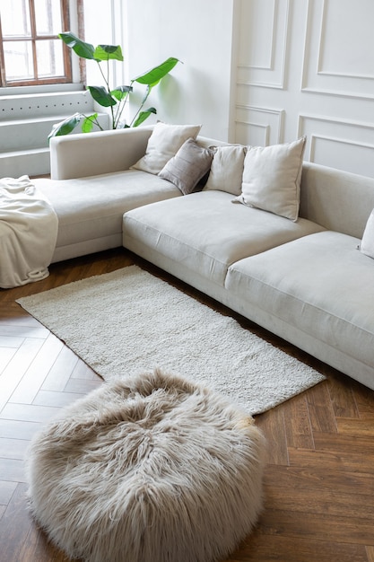 Minimalistic interior of an ultra modern open plan apartment with white and gray walls with a relief and gray stylish upholstered furniture and huge windows