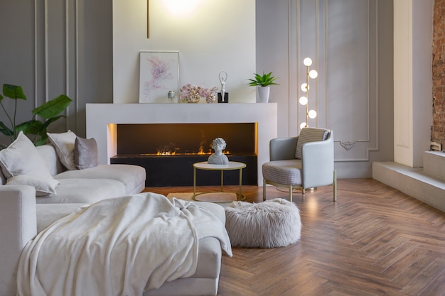 Minimalistic interior of an ultra modern open plan apartment with white and gray walls with a relief and gray stylish upholstered furniture and huge windows