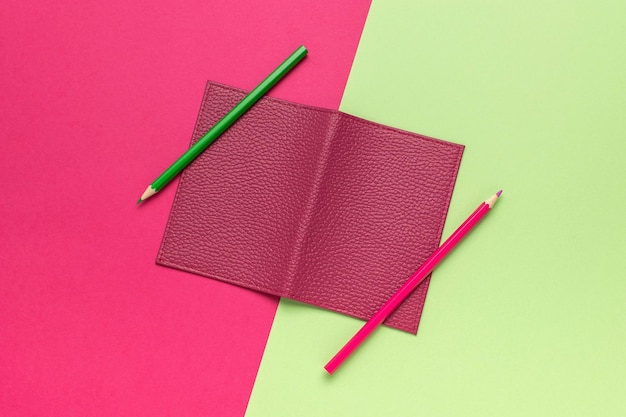 Photo minimalistic leather notebook with pencils on vibrant green and pink background