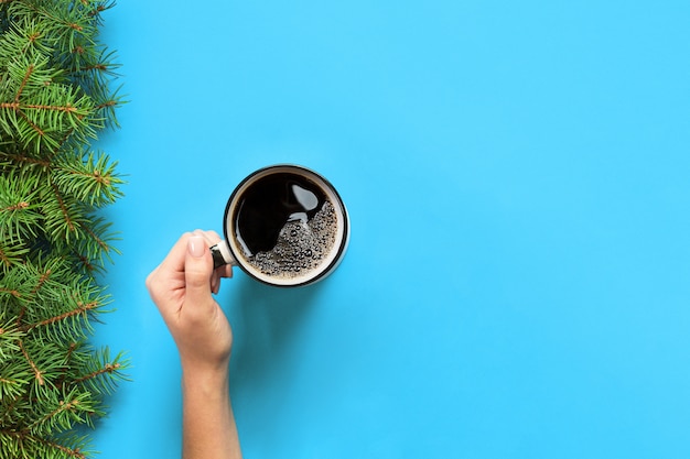 Minimalistic style woman hand holding a mug of coffee on blue 