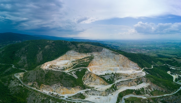 Mining on mountain in valley of rhodope mountains with forests and cloudy sky panorama top view