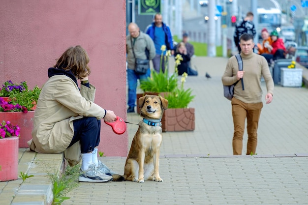 Minsk Belarus May 31 2022 A guy with a dog on a leash is sitting on a busy street