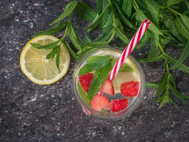 Mint leaves and a mug of cold water with lemon and berries