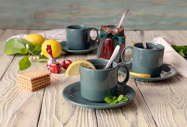 Mint tea in cups and lemons on a wooden table closeup