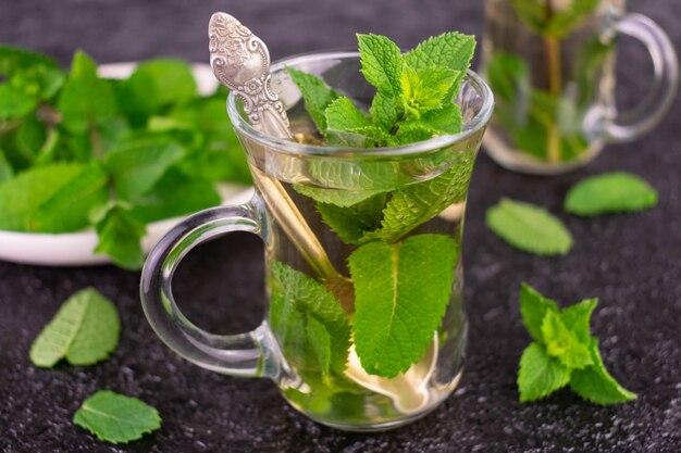 Mint tea in a transparent cup on a black background.Close-up.