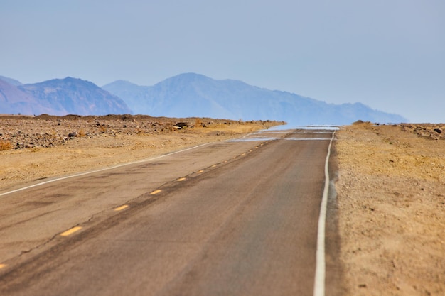 Mirage on road in desert landscape with mountains