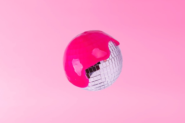 Mirror ball doused with pink paint on a pink background Creative music concept