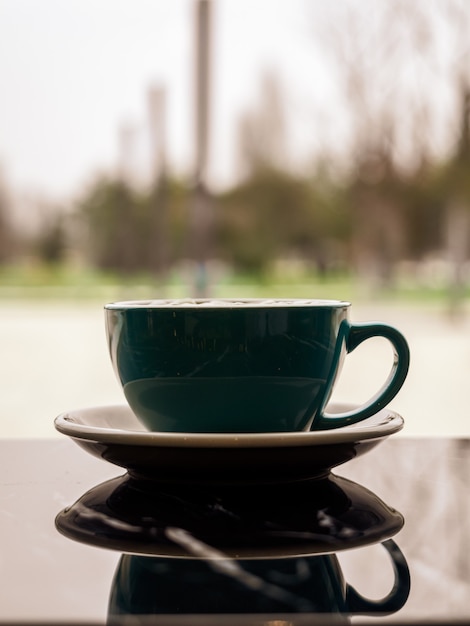 Mirror image of a beautiful stylish mug in the dark surface of the table