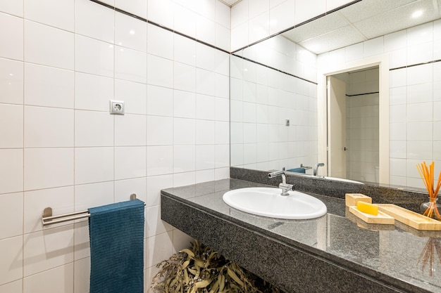 Mirror view in spacious bathroom with large stone countertop mirror and a sink with reflective white