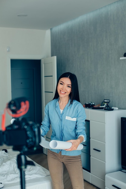 Mirthful female architect recording a new video about her project while being at home in the bedroom