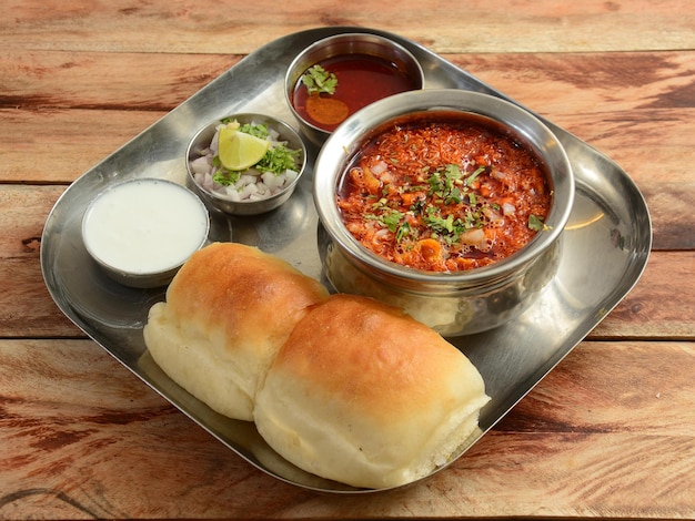 Misal Pav is a special dish in Maharashtra India The dish is eaten for breakfast or as a midday snack served over a rustic wooden background selective focus