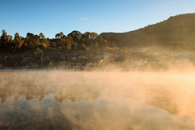 Misty morning sunrise over mountain with village around the river