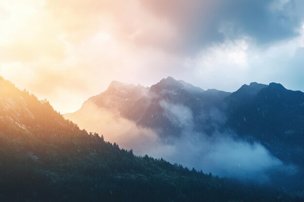 Misty mountain landscape at sunrise with soft clouds over the peaks and forest below