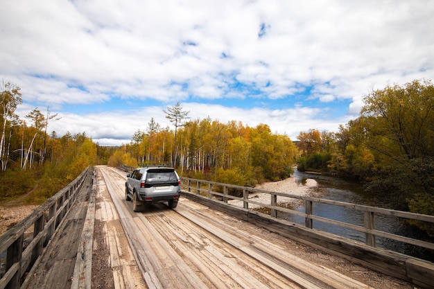 Mitsubishi Pajero Sport on wooden bridge in autumn forest