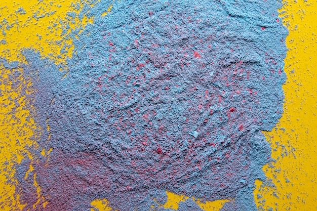 Mix of blue and red powder on a yellow background Copy space Abstract texture Top view