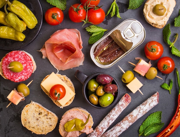 Mix of different snacks and appetizers. Spanish tapas on a black stone plate.