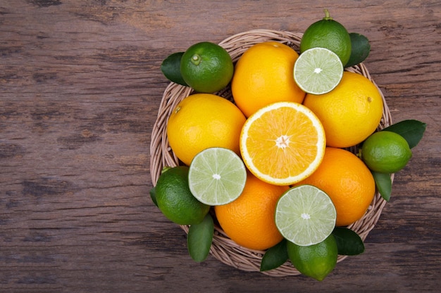 Mix of fresh citrus fruits in basket on wood