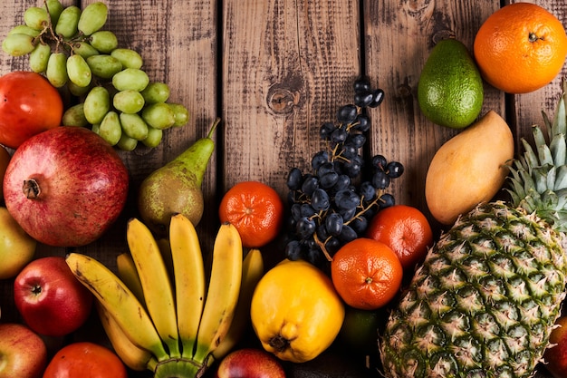 Mix of fresh juicy colorful exotic tropical fruits on wooden background top view with copy space