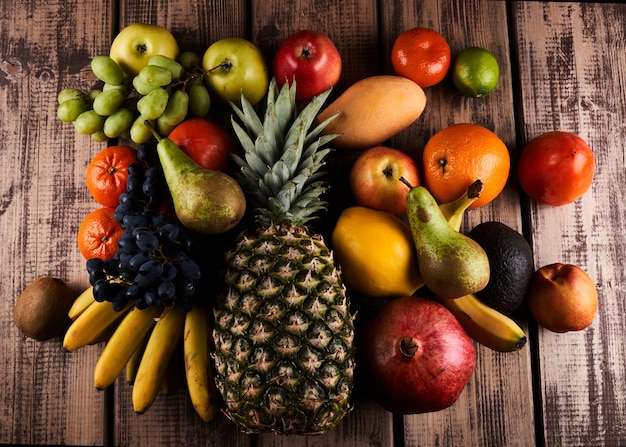 Mix of fresh juicy colorful exotic tropical fruits on wooden background top view