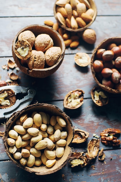 Mix of nuts in coconut bowls on dark wooden table, walnuts, almond, hazelnut, cashew, healthy various superfoods, selecitve focus