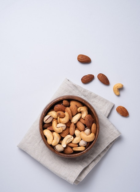 Mix of nuts on wooden bowl on light background