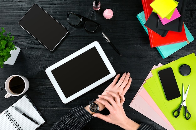 Mix of office supplies and gadgets on a wooden desk background view from above