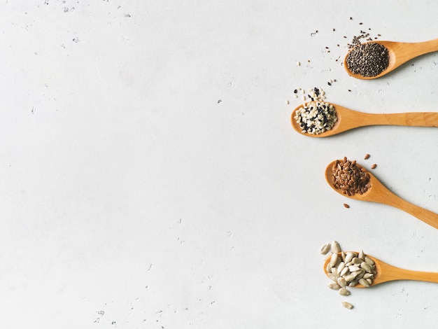 Mix of seeds in spoon close up on white background. Vegan and vegetarian food concept