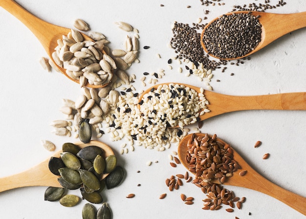 Mix of seeds in spoon close up on white background. Vegan and vegetarian food concept