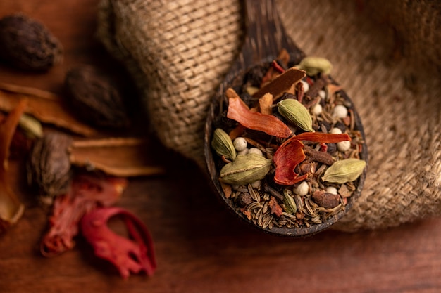 Mix spices and herbs in a wooden spoon on dark surface, Indian spices food and cuisine ingredients