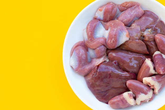 Mixed chicken entrails in white plate on yellow background