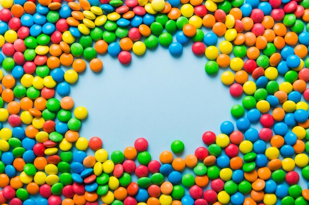 Mixed collection of colorful candy on colored background Flat lay top view frame of colorful chocolate coated candy