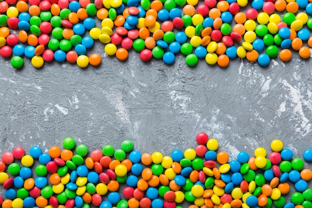 Mixed collection of colorful candy on colored background Flat lay top view frame of colorful chocolate coated candy