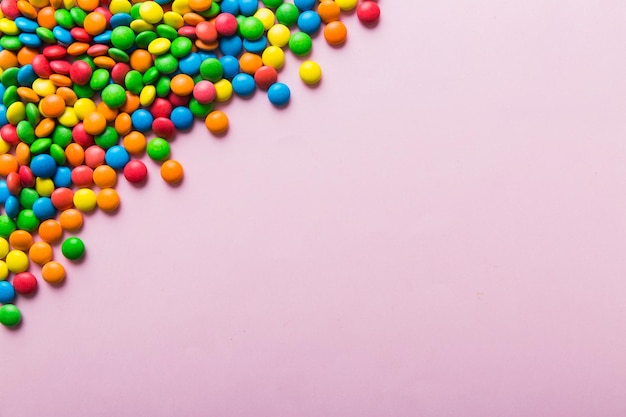 Mixed collection of colorful candy on colored background Flat lay top view frame of colorful chocolate coated candy