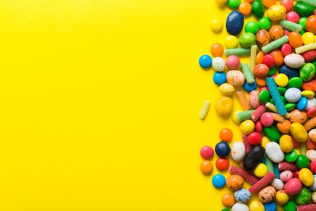 Mixed collection of colorful candy on colored background Flat lay top view frame of colorful chocolate coated candy