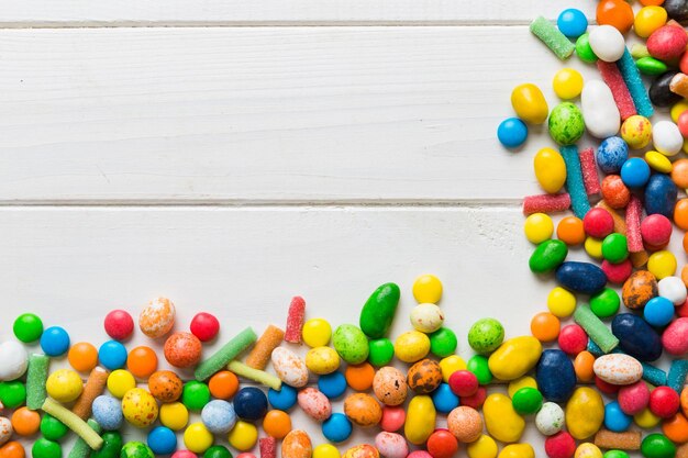 Mixed collection of colorful candy on colored background Flat lay top view frame of colorful chocolate coated candy