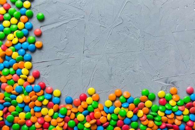 Mixed collection of colorful candy on colored background Flat lay top view frame of colorful chocolate coated candy