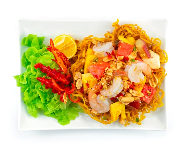 Mixed Fruit Spicy salad with deep fried Egg noodles bowl Thaifood fusion Style decoration carved chili and vegetables topview