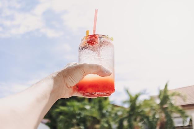 Mixed fruits pink soda against sunny sky of summer