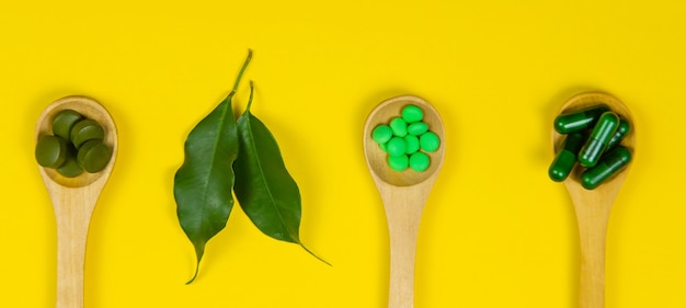 Mixed herbal tablets on a wooden spoon. Food supplement. Selective focus