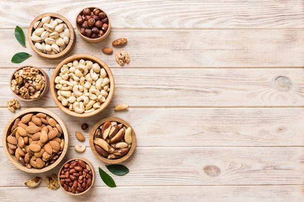 Mixed nuts in wooden bowl Mix of various nuts on colored background pistachios cashews walnuts hazelnuts peanuts and brazil nuts