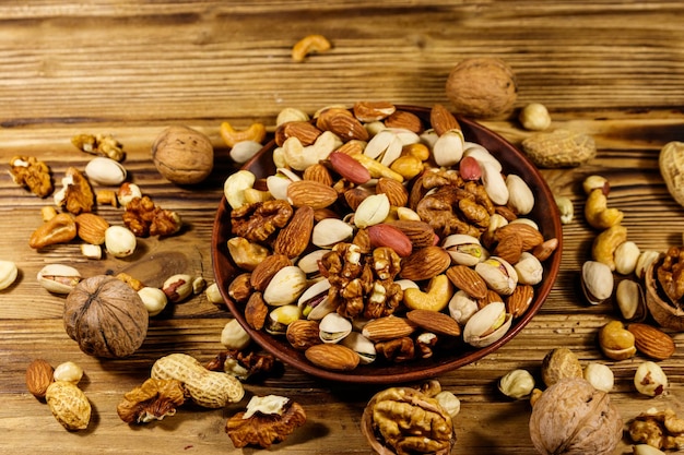 Mixed nuts on wooden table Walnuts pistachio almond peanut cashew hazelnut in ceramic bowl Healthy eating concept