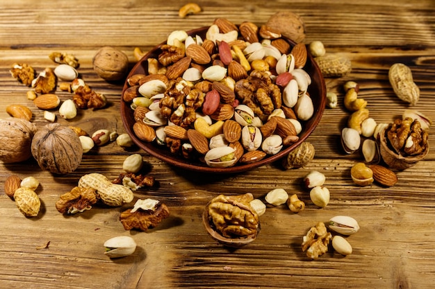 Mixed nuts on wooden table Walnuts pistachio almond peanut cashew hazelnut in ceramic bowl Healthy eating concept