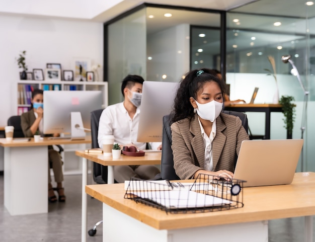 Mixed race of African and Asian business people wearing face masks in the office